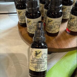 Bottles of herbal tincture with handwritten labels on a table.